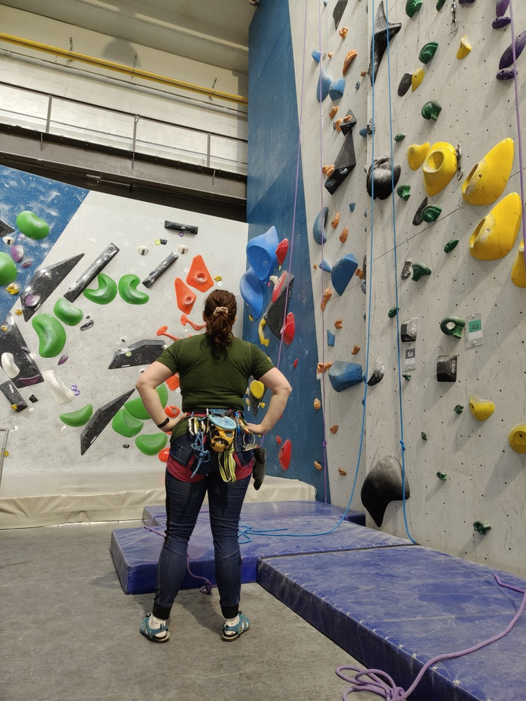 Zdjęcie kobiety z tyłu obserwującej sztuczną ściankę wspinaczkową