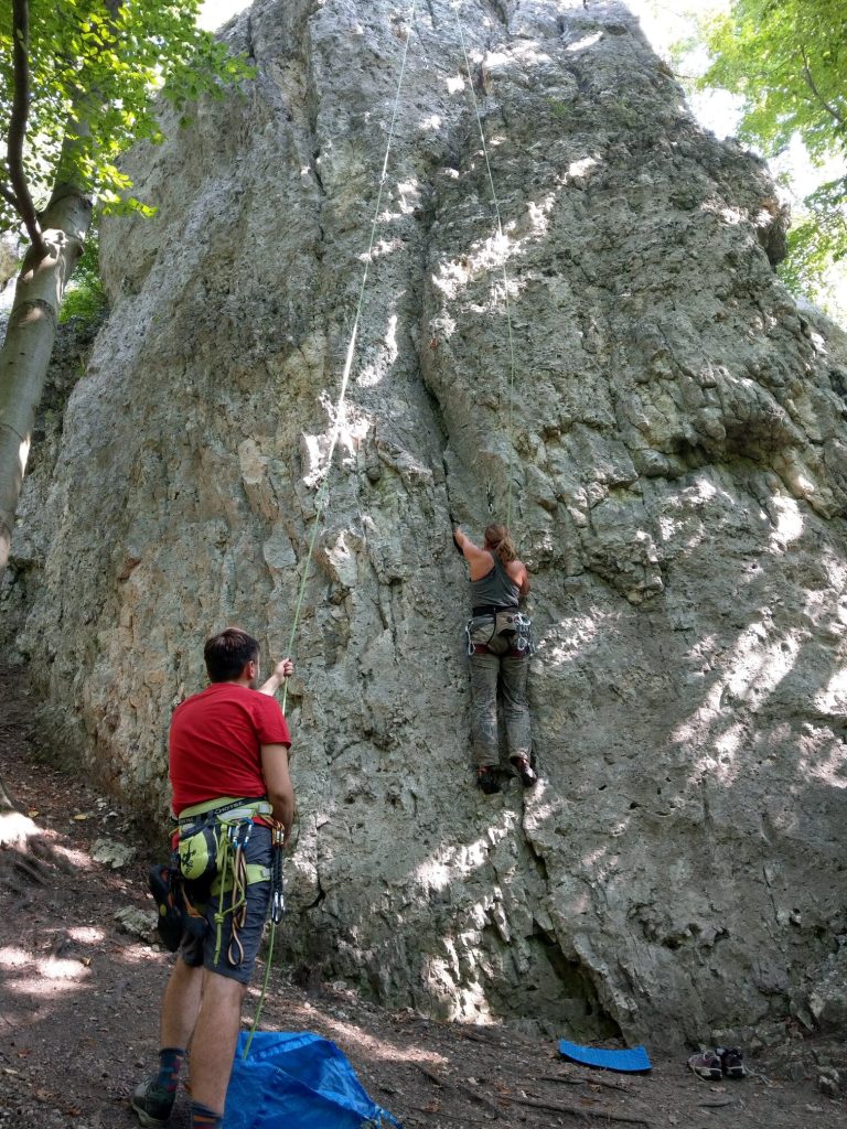 Jurajska skała - Wielka Ostryszniańska w Dolinie Dłubni. Kobieta wspina się na skałkę