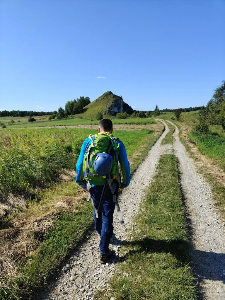 Mężczyzna idzie wśród jurajskich pól w kierunku Powroźnikowej skały